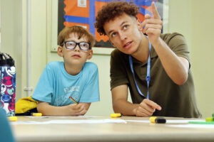 A male teacher draws the pupils attention and focus to a point in the classroom