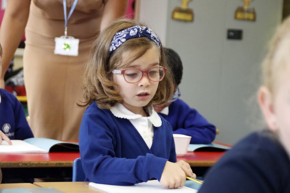 A primary school girl holds a pencil in anticipation of writing in a workbook