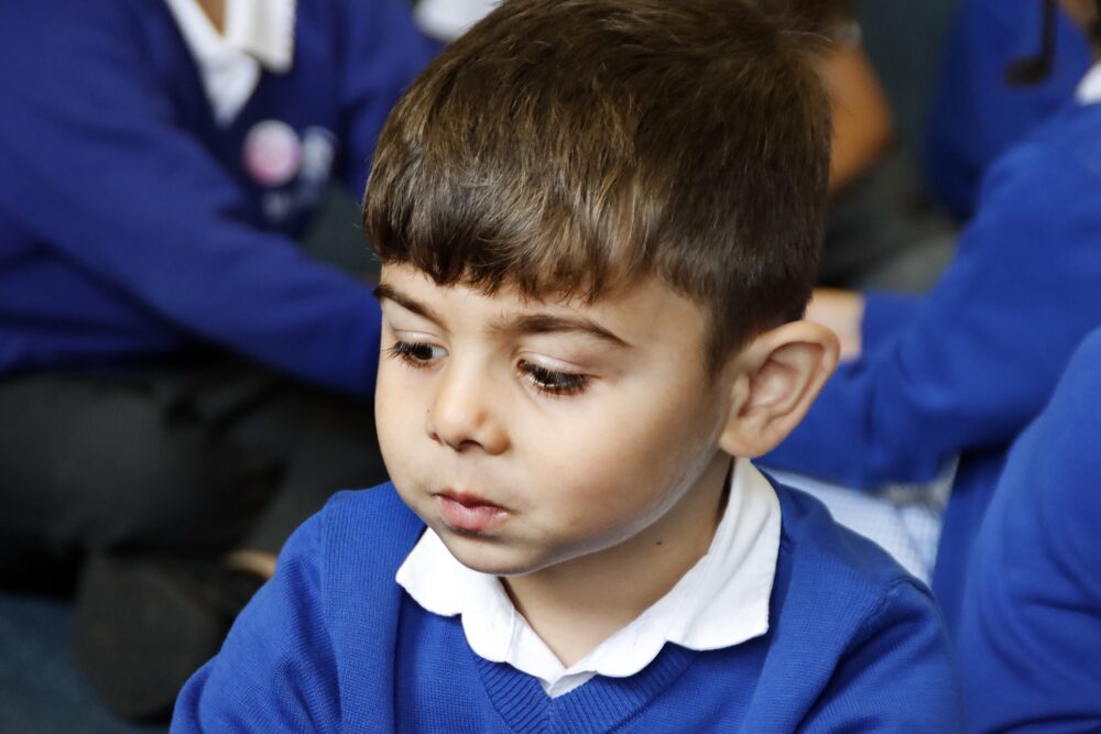 A young boy looks down to pay attention to the group sessions
