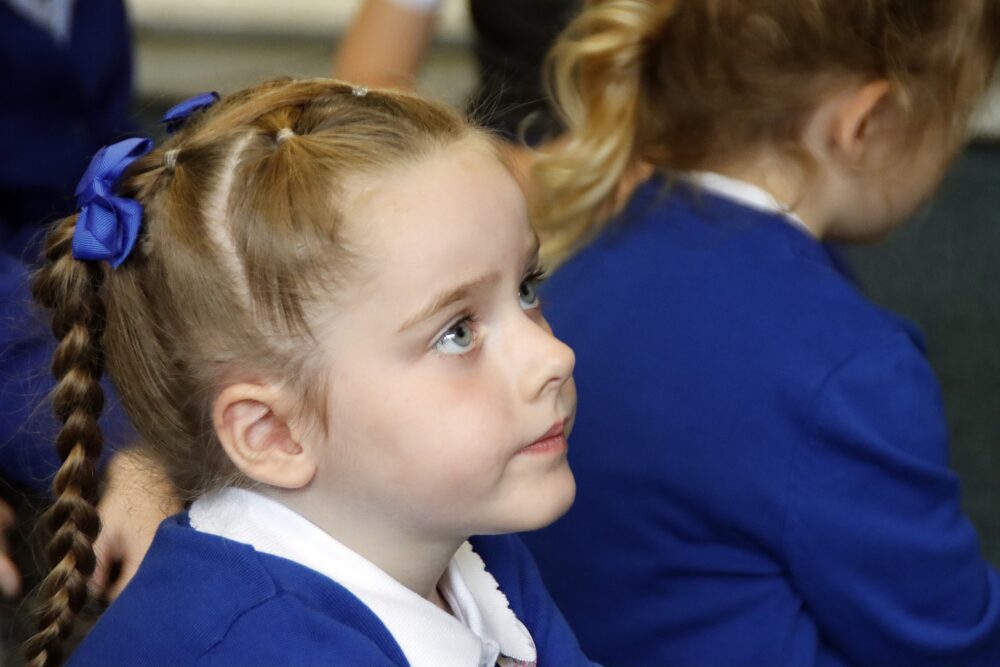 A young pupil with ribbons and braids gazes forward