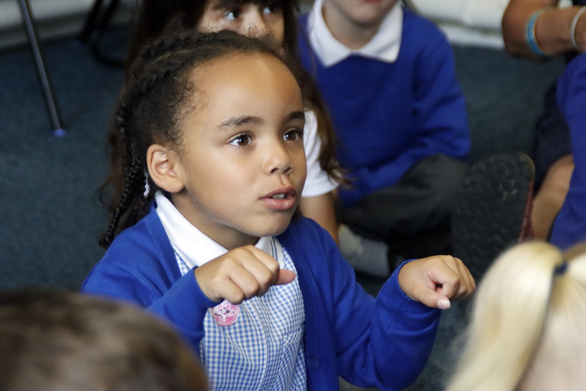 A young girl pupil makes gestures perhaps suggesting riding a bike