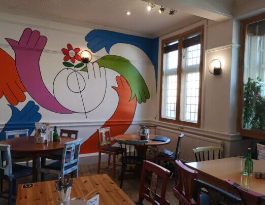 A cafe with a bright abstract mural on the wall
