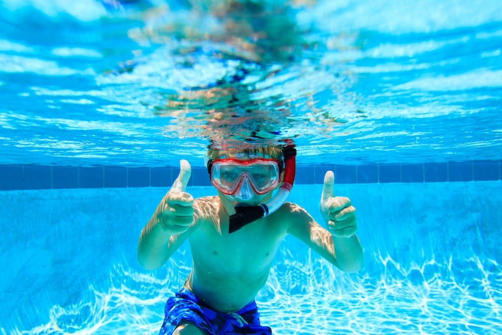 happy little boy swimming underwater with thumbs up